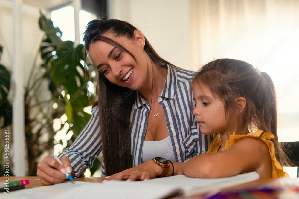 Caucasian mother and little daughter have fun drawing in album on family weekend together Caucasian mother and little daughter have fun drawing in album on family weekend together