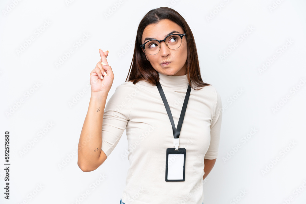 Young caucasian woman with ID card isolated on white background with fingers crossing and wishing the best Young caucasian woman with ID card isolated on white background with fingers crossing and wishing the best