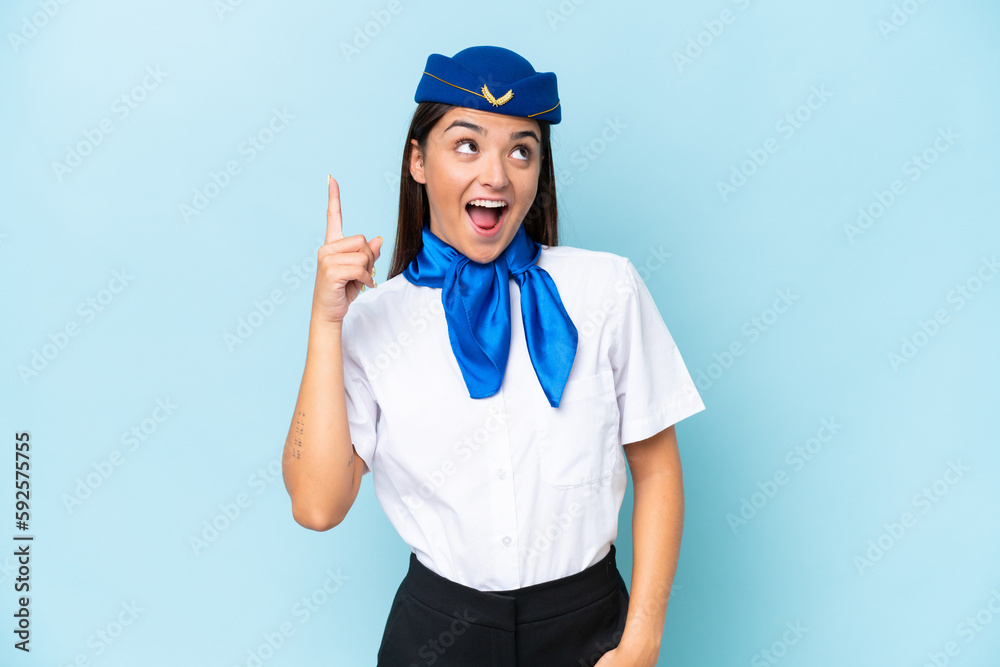 Airplane stewardess caucasian woman isolated on blue background pointing up and surprised Airplane stewardess caucasian woman isolated on blue background pointing up and surprised