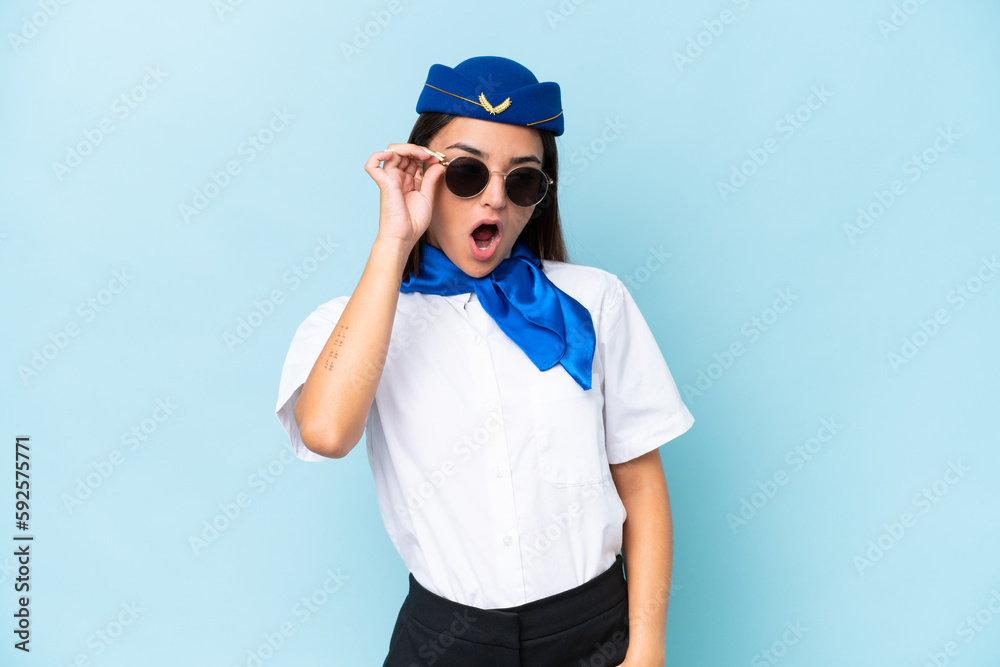 Airplane stewardess caucasian woman isolated on blue background with glasses and surprised Airplane stewardess caucasian woman isolated on blue background with glasses and surprised