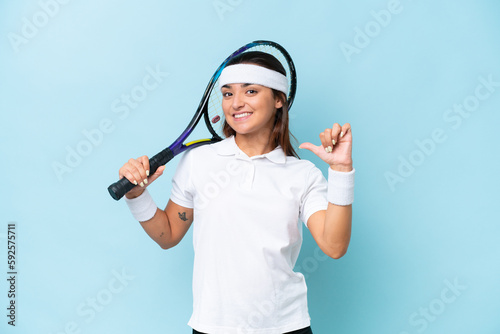 Young tennis player woman isolated on blue background proud and self-satisfied
