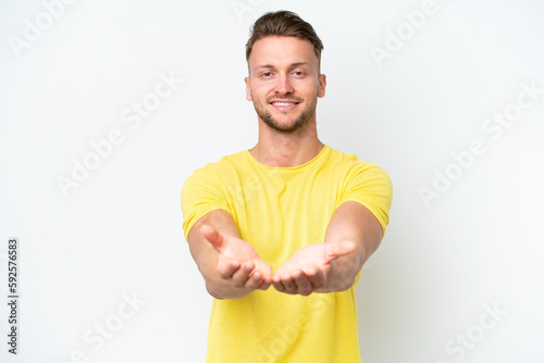 Young blonde caucasian man isolated on white background holding copyspace imaginary on the palm to insert an ad
