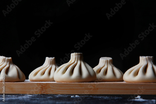 Preparation of khinkali. A slide of homemade raw khinkali dumplings in close-up on the table. Georgian cuisine. Selective focus. Copy space. photo