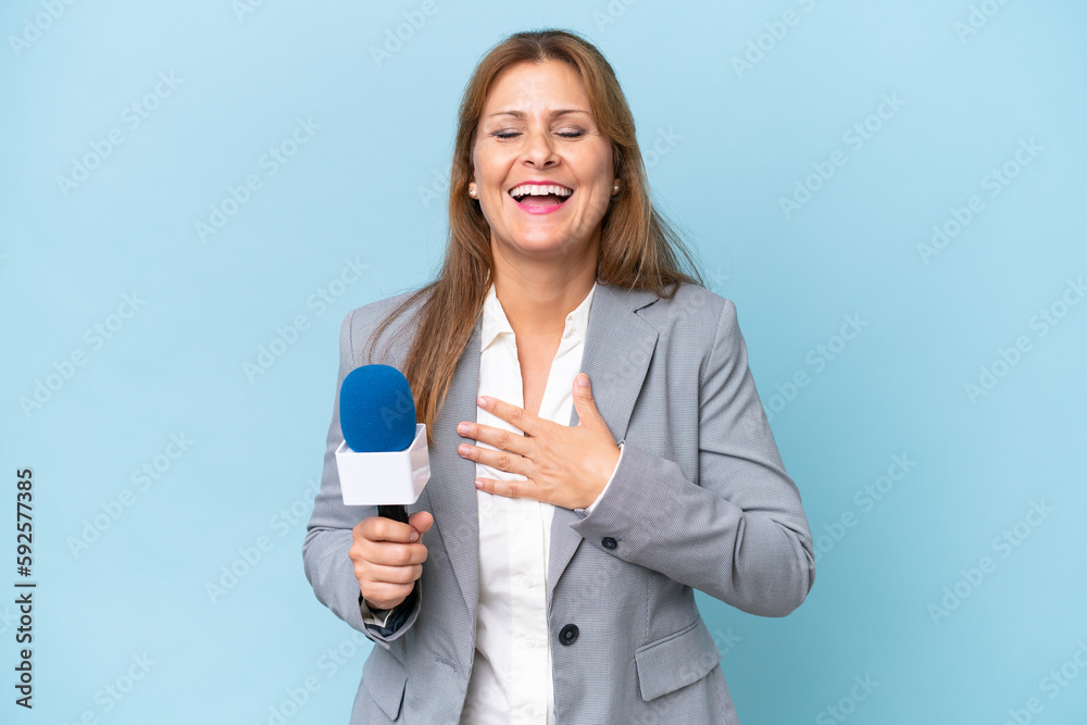Middle-aged TV presenter woman over isolated blue background smiling a lot Middle-aged TV presenter woman over isolated blue background smiling a lot