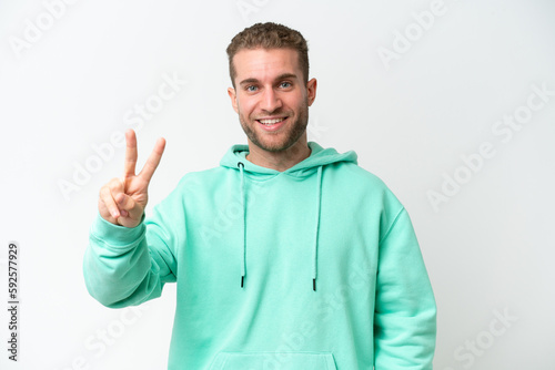 Young handsome caucasian man isolated on white background smiling and showing victory sign © luismolinero