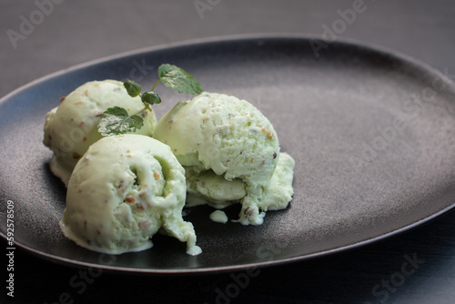 pistachio ice cream in a black waffle cone. Nutty green dessert with cinnamon sticks on a black background