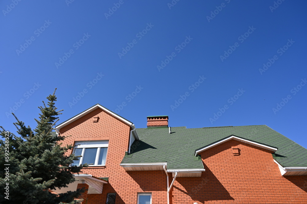 View of the second floor against the blue sky of a private house made of red brick.