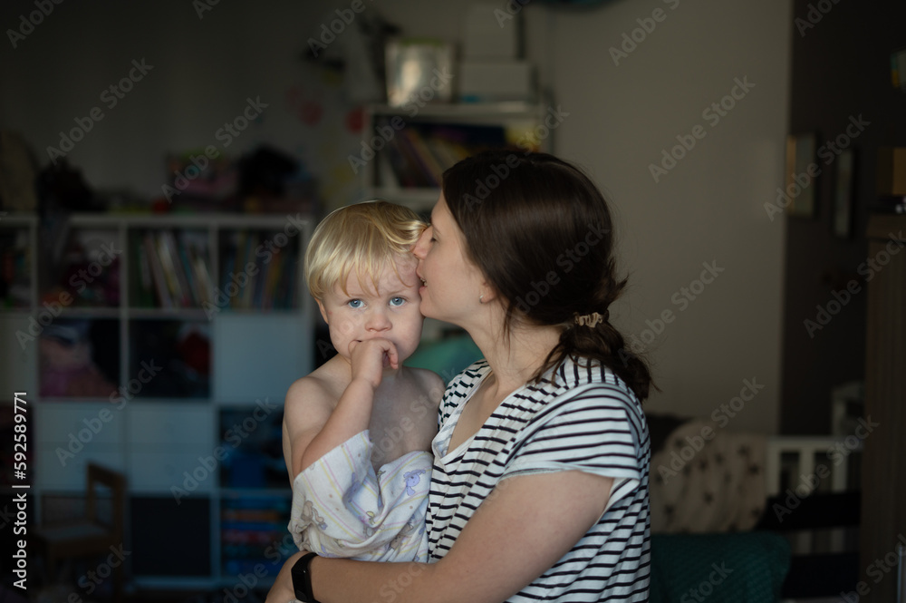A young woman kissing a boy in her arms after a bath A young woman kissing a boy in her arms after a bath