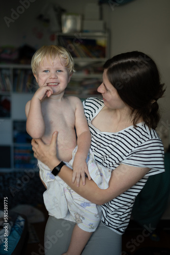 A young woman holds a boy in her arms after a bath