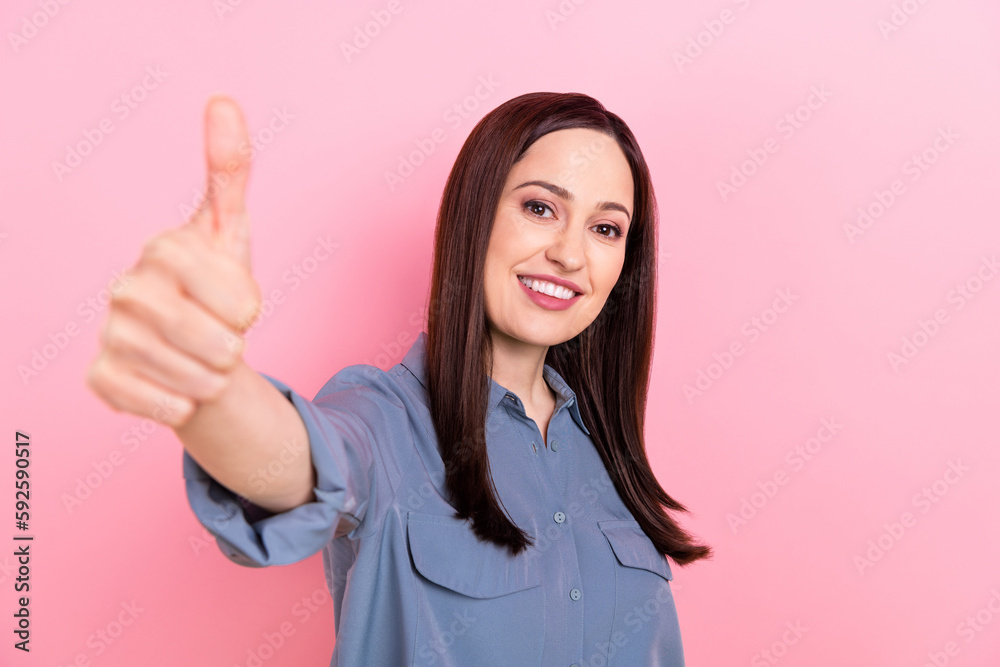 Photo of positive cheerful lovely lady wear trendy blue clothes demonstrate thumb up nice offer isolated on pink color background Photo of positive cheerful lovely lady wear trendy blue clothes demonstrate thumb up nice offer isolated on pink color background