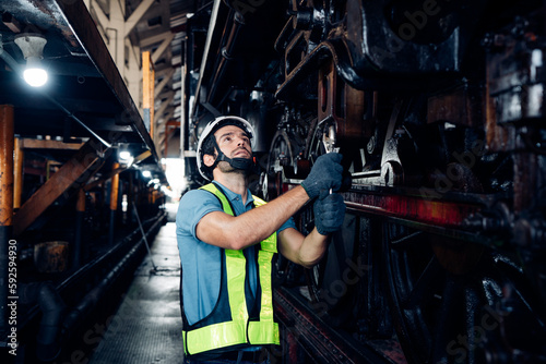 Male engineer maintenance locomotive engine wearing safety uniform, helmet and gloves work in locomotive repair garage. 