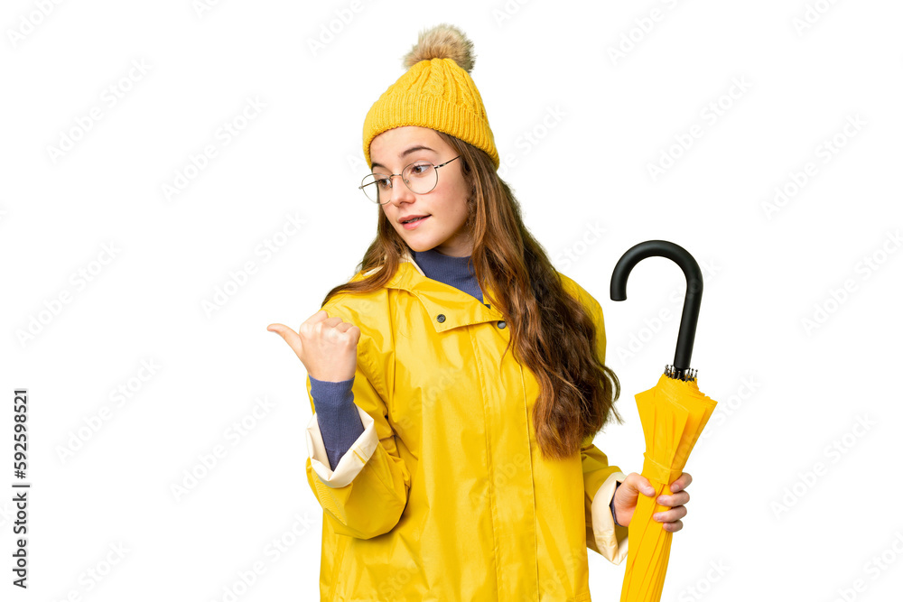 Teenager girl with rainproof coat and umbrella over isolated chroma key background pointing to the side to present a product Teenager girl with rainproof coat and umbrella over isolated chroma key background pointing to the side to present a product