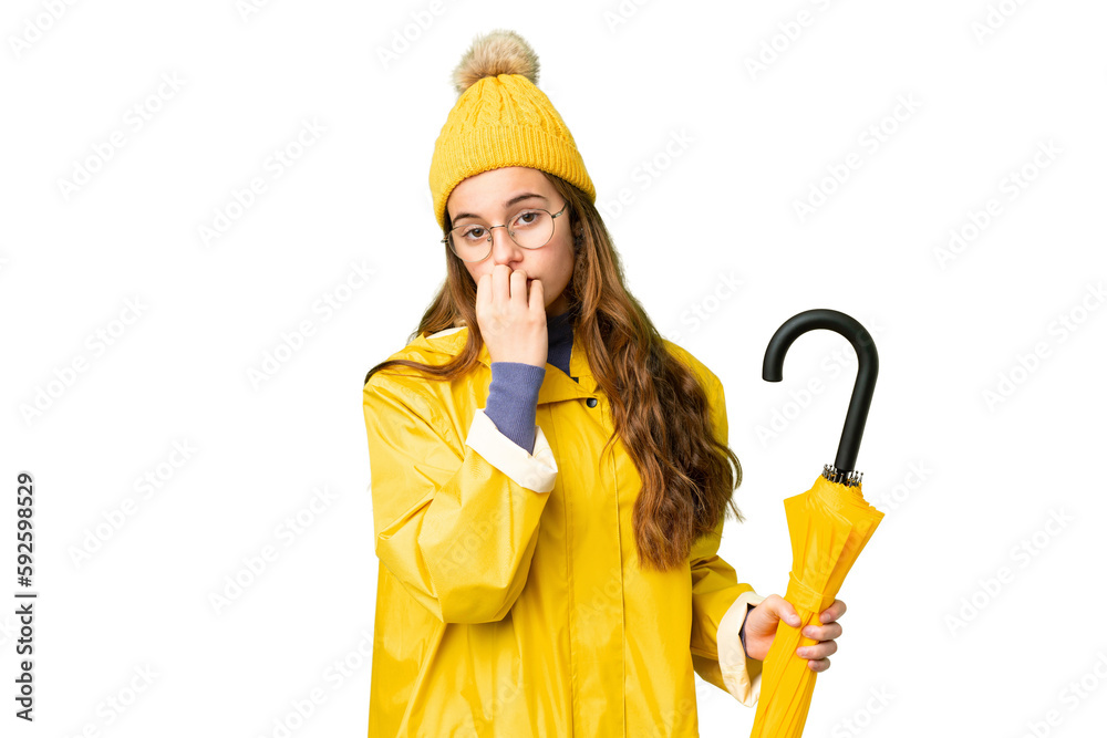 Teenager girl with rainproof coat and umbrella over isolated chroma key background having doubts