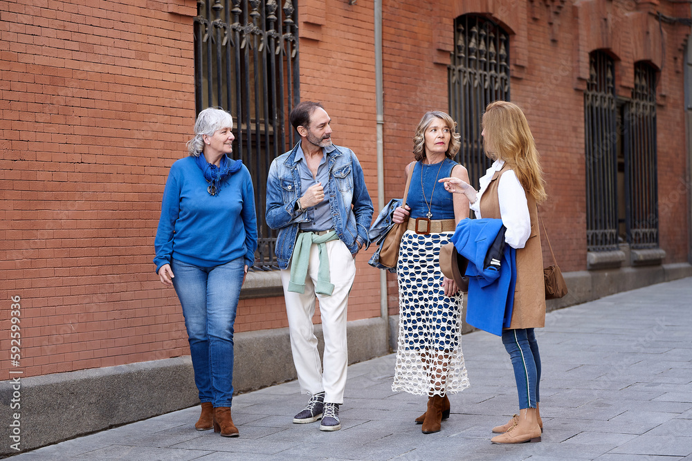 Four close friends in their 60s strolling along the street, chatting
