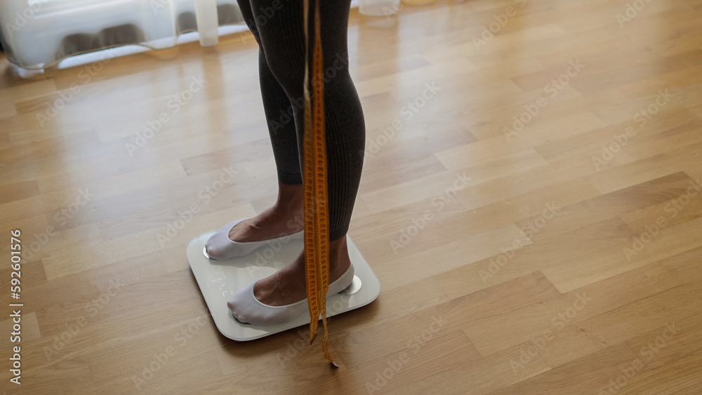 Woman Measuring Body Weight On Weighing Scale At Home. Close up of a