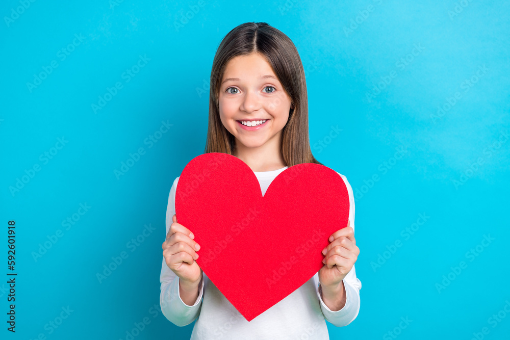 Photo of good mood nice girl with long hairstyle wear white long sleeve hold large figure paper heart isolated on blue color background Photo of good mood nice girl with long hairstyle wear white long sleeve hold large figure paper heart isolated on blue color background