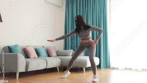 Athletic woman sports workout at home, squats. Home workout. Slim female stretching at home and weight loss workout in a living room.