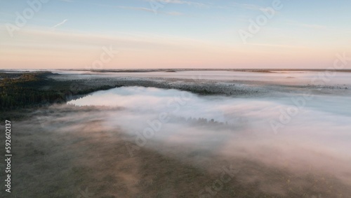 Fototapeta Naklejka Na Ścianę i Meble -  Beautiful view of a lake with a cloudy sky and little morning mist