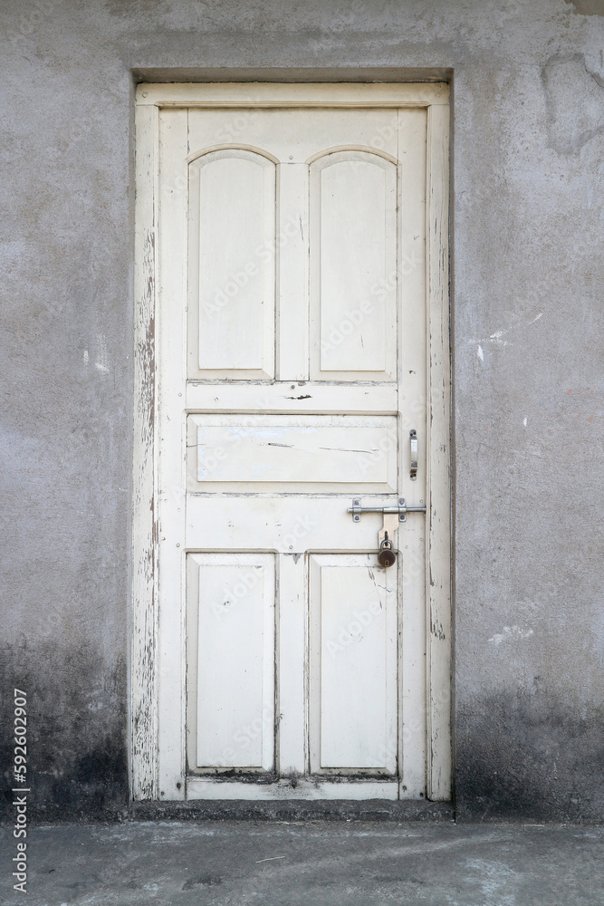Fototapeta premium An old white wooden door, bolted and padlocked.