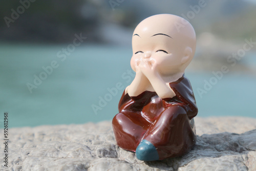 Little buddha or buddhist monk covered his mouth with both hands. Conceptual photo about speech control. Silence is gold. photo