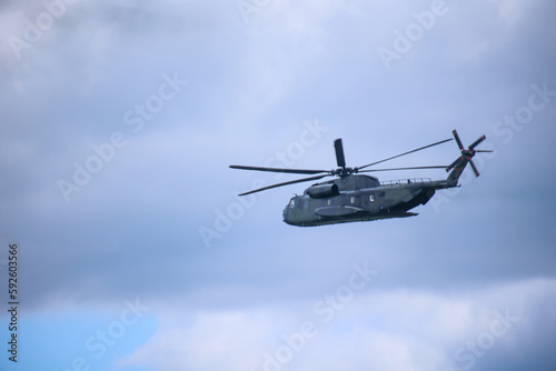 Ein militärischer Hubschrauber mit offener Heckklappe am Himmel. photo