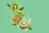 Creative layout made from Sliced of kiwi and water Splashing on a green background.