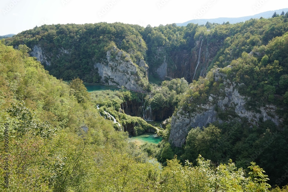 Scenic shot of a lake surrounded by cliffs covered in green plants at Plitvice Lakes National Park