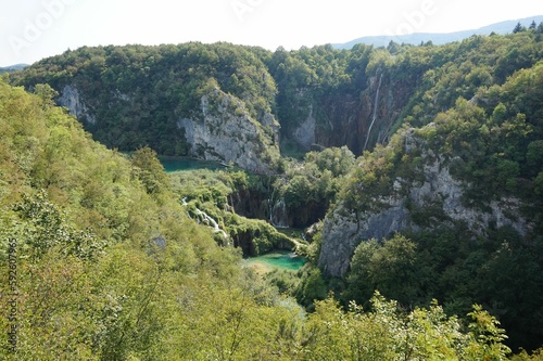 Scenic shot of a lake surrounded by cliffs covered in green plants at Plitvice Lakes National Park