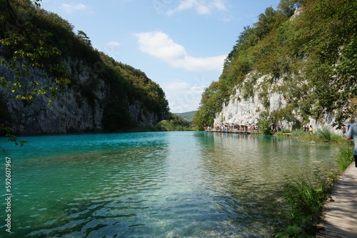 Blue still lake surrounded by rocky cliffs and green plants at Plitvice Lakes National Park