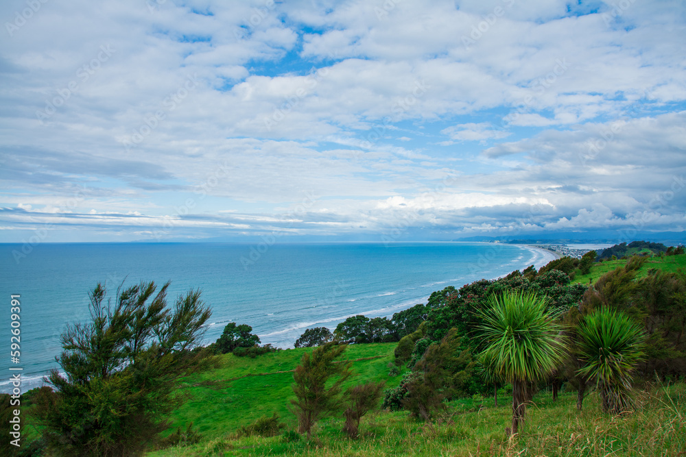 Breathtaking aerial view over vast ocean beach surrounded by distant mountains. Mist rising over water. Patches of blue sky seen through the clouds. Whakatane, North Island, New Zealand Breathtaking aerial view over vast ocean beach surrounded by distant mountains. Mist rising over water. Patches of blue sky seen through the clouds. Whakatane, North Island, New Zealand