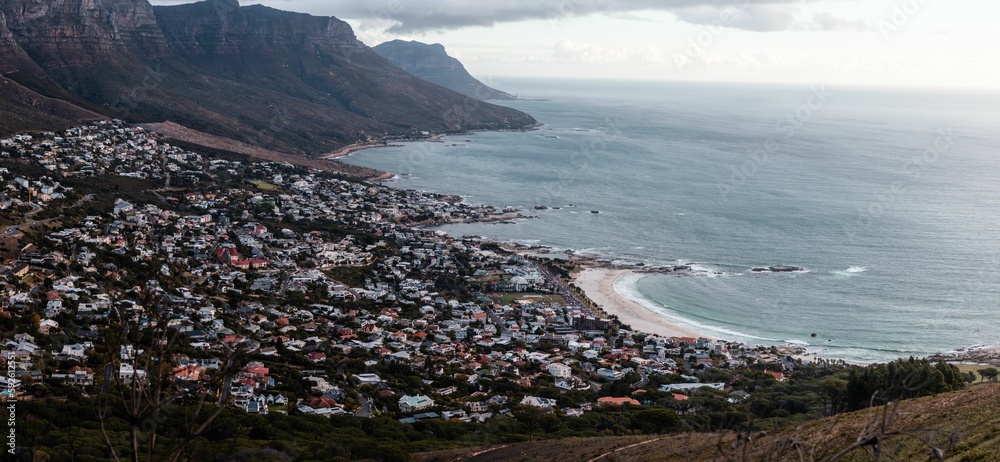 Naklejka premium Cityscape view from a mountain of Camps Bay houses by the sea in Cape Town, South Africa