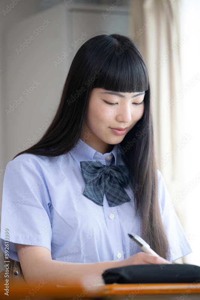 Female high school student in short sleeves studying by classroom window Spring/Summer Copy space available Vertical Female high school student in short sleeves studying by classroom window Spring/Summer Copy space available Vertical