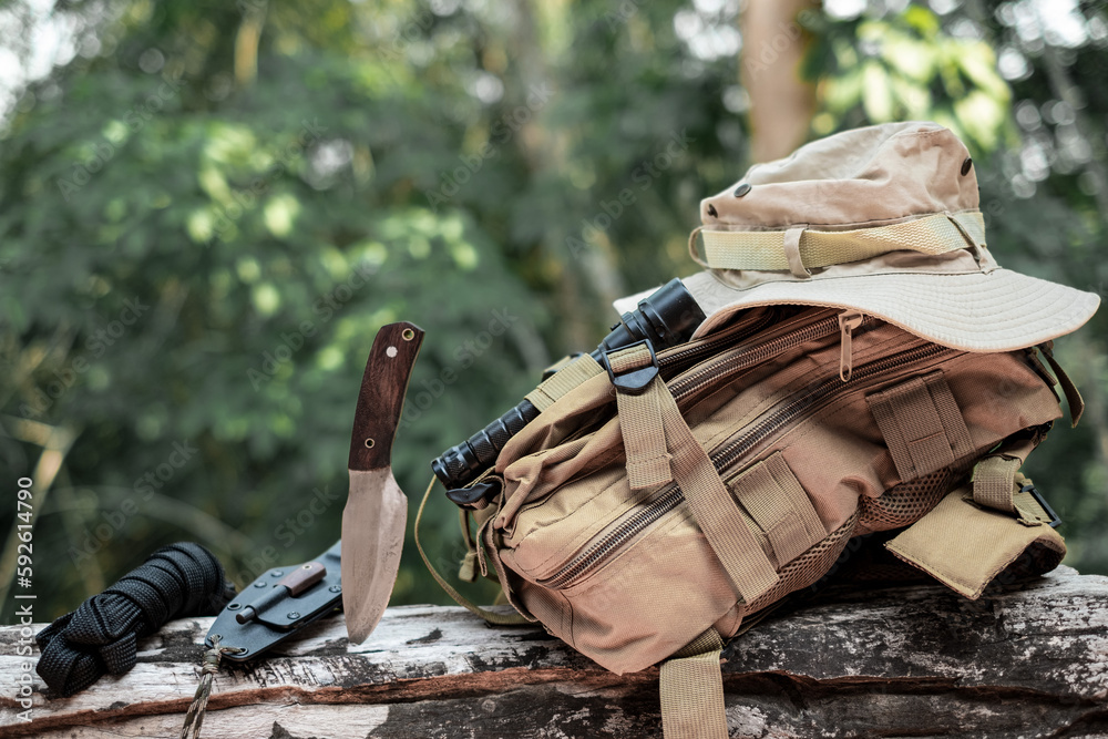 Equipment for survival bucket hat backpack hiking knife camping flashlight  resting on wooden timber in the background is a jungle Stock Photo | Adobe  Stock