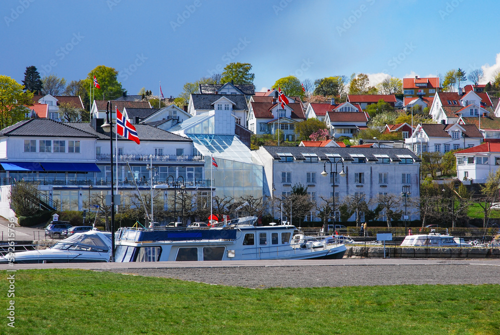 Obraz premium A view of sea yachts in the harbor and residential houses and other buildings in the small port town of Asgardstrand, Norway.
