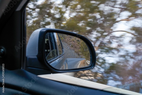 Closeup shot of car's sidemirror from inside the car while driving against blur nature background © Lucija Kanižaj/Wirestock Creators
