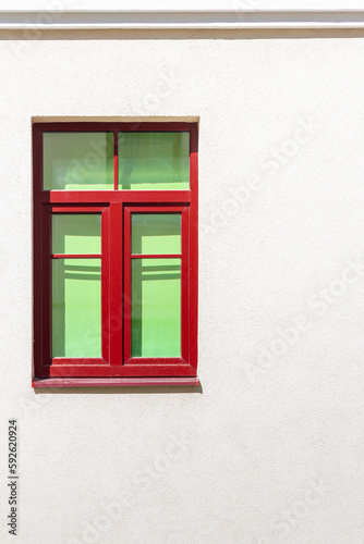 Red window frame on a light background wall facade of the house.