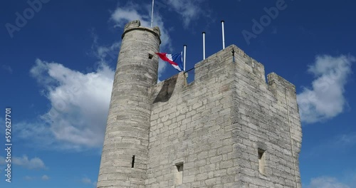 View of châtelet on top of Philipe-le-Bel Tower in Villeneuve-lès-Avignon, France, with slowly moving clouds in a blue sky and french flag moving in the wind