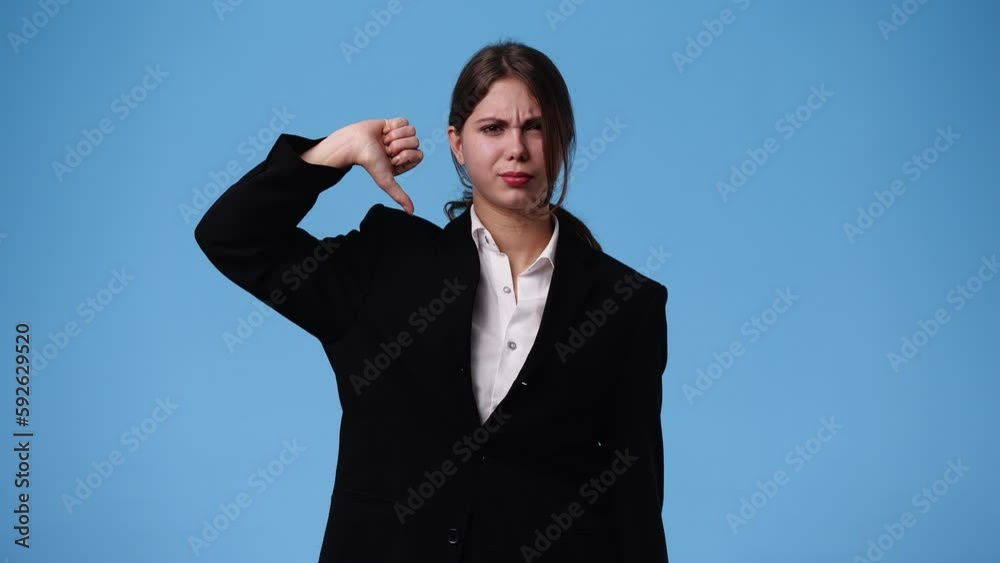 4k video of one girl with negative facial expression showing thumb down over blue background. 4k video of one girl with negative facial expression showing thumb down over blue background.