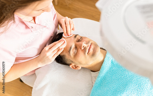 Beautician doing face treatment in beauty salon to a man.. © Zoran Zeremski