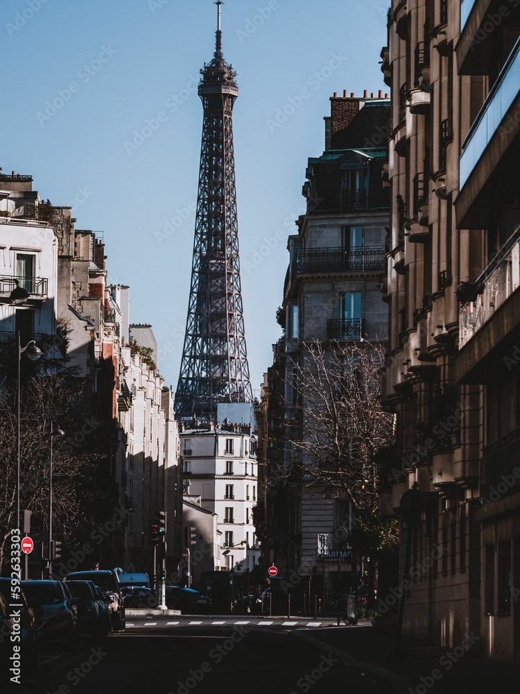 Fototapeta premium Vertical shot of the Eiffel tower behind buildings