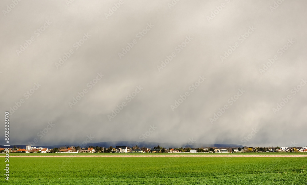 rain over a village and a fresh green meadow in the foreground the spring rain over a village and a fresh green meadow in the foreground the spring