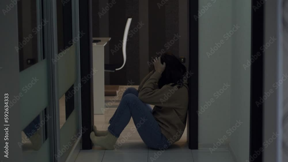 Frustrated person sitting on kitchen floor suffering from emotional pain. Depressed worried young woman in crisis Frustrated person sitting on kitchen floor suffering from emotional pain. Depressed worried young woman in crisis