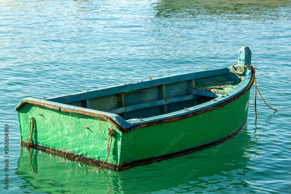 Green boat in sunlit water reflecting sunlight and objects around Green boat in sunlit water reflecting sunlight and objects around