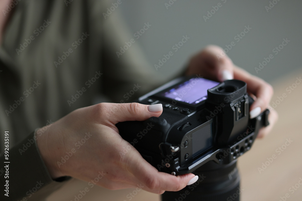 Hands of woman holding professional camera with small screen