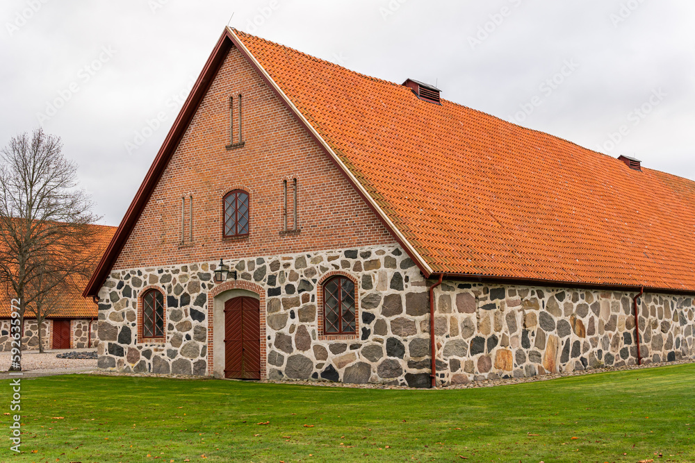 An old ancient building in Scandinavian style from big stones and bricks. Rural area, village, big farm.