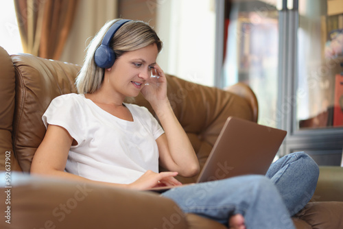 Woman works on laptop and listens to music in headphones photo