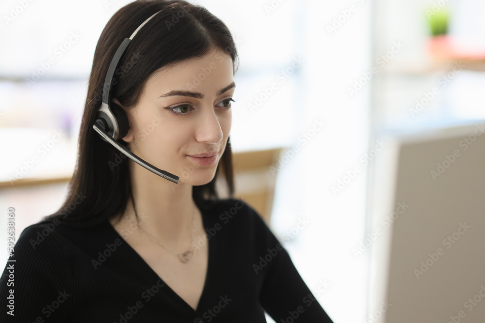 Brunette woman with headset looks at monitor of computer Brunette woman with headset looks at monitor of computer