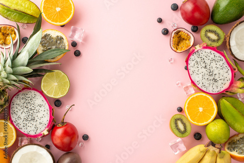 Summer fruit platter. A mouth-watering flat lay top view of exotic fruits like dragon fruit  kiwi  papaya  pineapple  orange  tomarillo  passion fruit  bananas and coconut  on a pink background