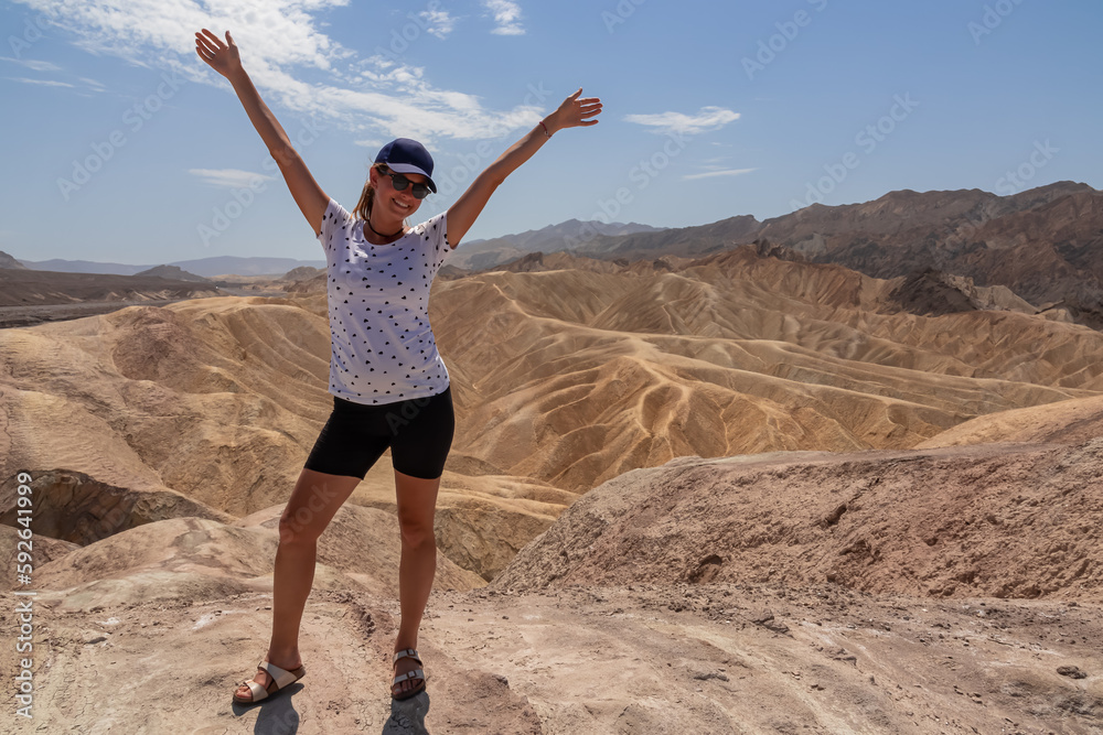 Woman with scenic view Badlands of Zabriskie Point, Furnace creek, Death Valley National Park, California, USA. Erosional landscape of multi hued Amargosa Chaos rock formations, Panamint Range in back Woman with scenic view Badlands of Zabriskie Point, Furnace creek, Death Valley National Park, California, USA. Erosional landscape of multi hued Amargosa Chaos rock formations, Panamint Range in back