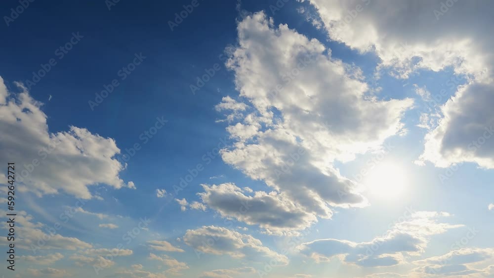 Beautiful white clouds in the blue sky and the rays of the bright sun. The movement of clouds across the sky. Timelapse 4k.